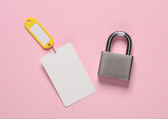 Plastic key card with tag and metal lock on pink background.