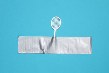 Tennis racquet fixed with adhesive tape on blue background.