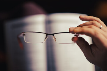 Glasses in a female hand. The concept of poor eyesight, reading books, learning.