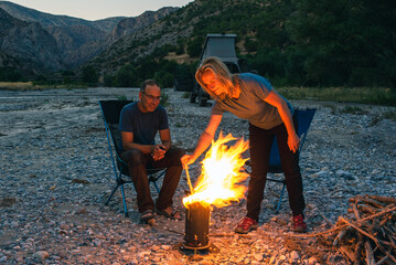 A traveling couple enjoys an evening campfire in a river valley.