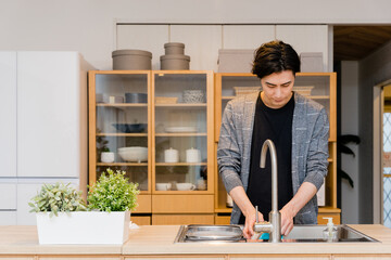 自宅のキッチンで食器の洗い物をする30代の男性