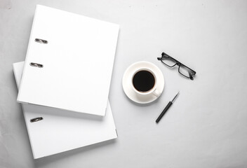 White Binder folders with coffee cup, eyeglasses on gray background. Business concept. Top view
