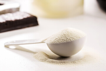 spoon with Creatine, whey or casein, whey supplements, protein bar for physical exercises, gym in the background, muscle mass gain
