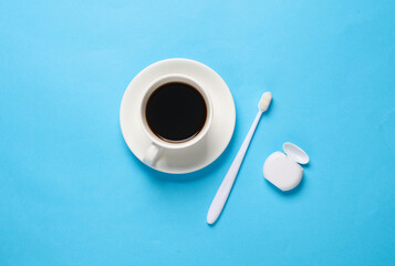Teeth whitening. Coffee cup and toothbrush with dental floss on blue background