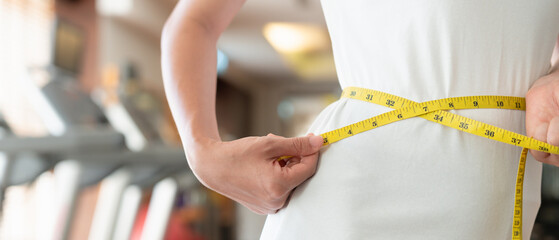 Diet and dieting. Beauty slim female body use tape measure. Woman in exercise clothes achieves...