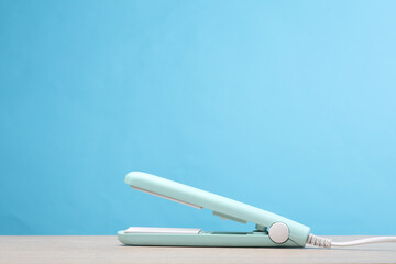 Hair iron on the table, blue background