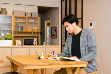 リビングでパソコンを開いて勉強をする30代の社会人の日本人男性
