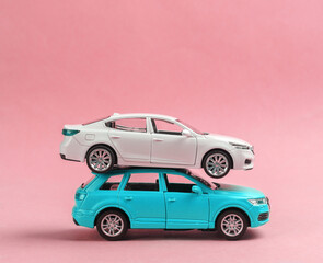 Two toy car models on a pink background