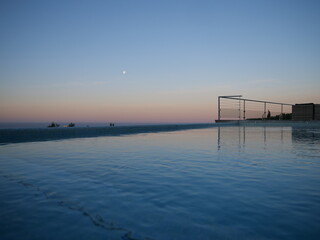 Sonnenuntergang am Pool, im Hintergrund das Meer