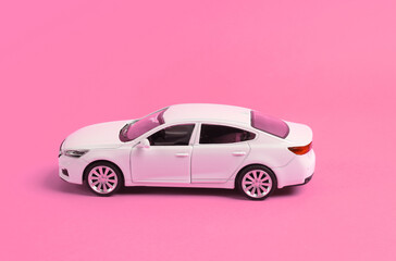 Mini model of white toy car on pink background