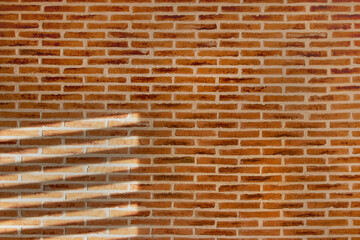Rustic brick wall texture for backgrounds. Striped light from a window projected on the wall.