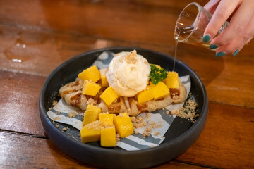 Croffle, hybrid of a croissant and waffle with Mango, ice-cream and honey served on plate