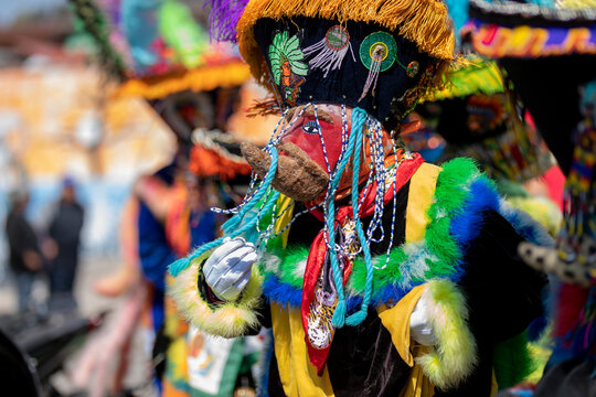 A person with a colorful chinelo costume, dancing in a carnival in Mexico