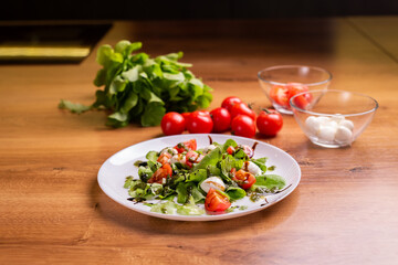 Plate of healthy classic close-up caprese salad with mozzarella cheese tomatoes and basil in kitchen - italian cuisine