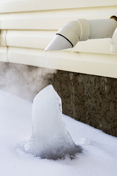 Close-Up Of Furnace Exhaust Pipe On Exterior Of House With Ice Block Forming; Calgary, Alberta, Canada