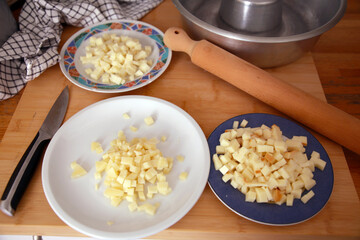 Cheeses pieces for the preparation of a traditional savory pie, with a rolling pin, a knife, and a pan