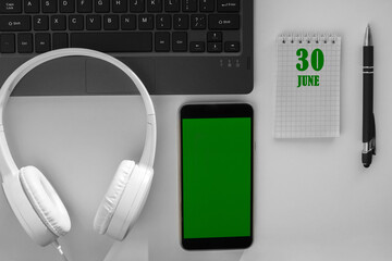 calendar date on a light background of a desktop and a phone with a green screen. June 30 is the...