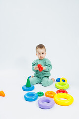 Fototapeta na wymiar Cheerful little boy sitting with plastic educational toys on a white background. Child and toys for development. Development of children's motor skills.