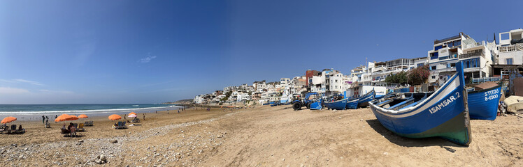 Morocco, Africa: panoramic view of old boats and the skyline on the beach of Taghazout, small...