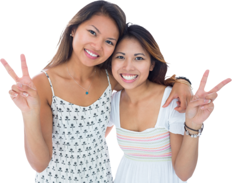 Two smiling young women making a peace gesture