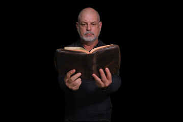 portrait of older man with beard doing reading isolated on black background