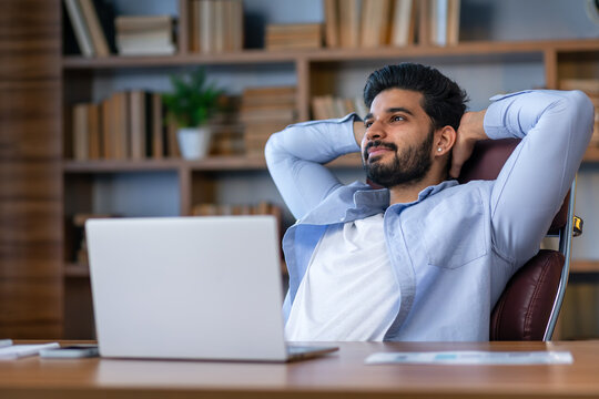 Relaxed Eastern Man Leaning Back In Chair, Resting After Online Work With Laptop, Millennial Arab Guy Sitting At Table With Computer In Home Office With Hands Behind Head And Looking Aside, Free Space