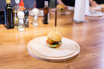 Delicious homemade burger of beef and cheese and vegetables on an wooden table. Fat unhealthy food close-up