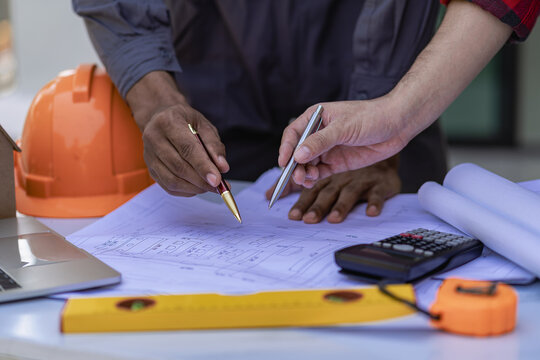 Engineer pointing at blueprint and using laptop to draw project design building construction architect Contractor and foreman meeting with floor plan for real estate development project industry