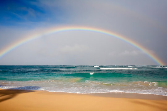 Rainbow spanning the ocean waves at Baldwin Beach on the North Shore of Maui near Paia; Maui, Hawaii, United States of America