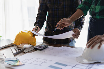 Engineer pointing at blueprint and using laptop to draw project design building construction architect Contractor and foreman meeting with floor plan for real estate development project industry