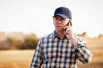 A man talking on a smart phone while monitoring and completing fall canola harvest; Alcomdale, Alberta, Canada