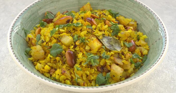 Kanda poha or Batata Poha - Indian breakfast meal made of flattened rice. Table spin.