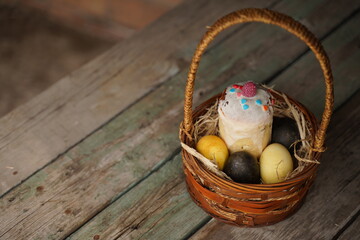 Easter eggs in the basket of wooden boards. Copy space