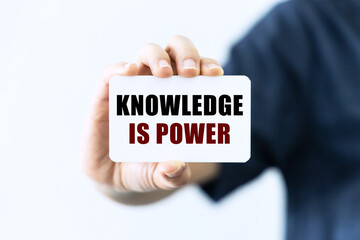 Knowledge is power text on blank business card being held by a woman's hand with blurred background. Business concept about knowledge.