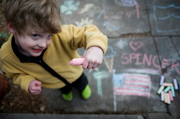 Young boy with chalk drawings on the ground; Lincoln, Nebraska, United States of America