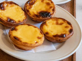 Un delicioso plato de cuatro tradicionales tartas de crema portuguesas o pasteis de nata con una corteza hojaldrada y una cubierta dulce caramelizada, un postre famoso y sabroso.
