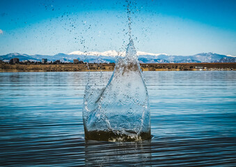 Rocky Mountain landscape with water splash in foreground, captured when rock was thrown into a lake.