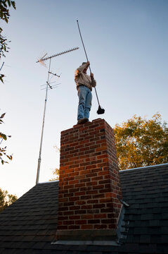 Man cleans the chimney of an old farmhouse; Cortland, Nebraska, United States of America