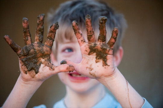 Smiling young boy holds up muddy hands; Dunbar, Nebraska, United States of America