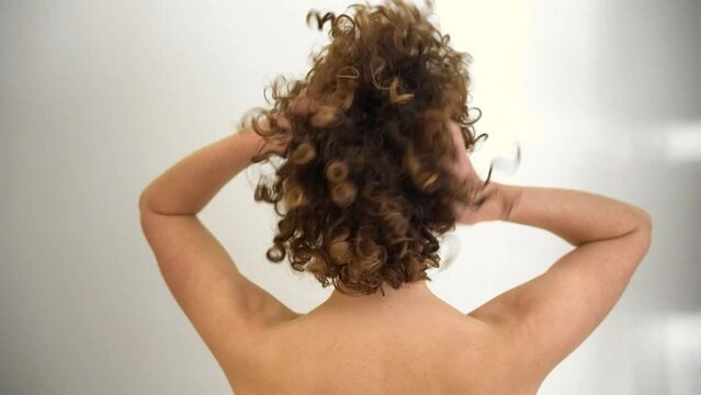 Rear view of attractive young woman playing with her hands in her curly afro hair