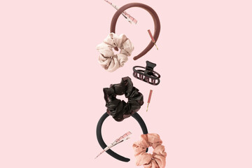 Hair accessories floating in the air against pastel pink background. Rubber band, hairclip, hairpin and headband levitating. Fun women fashion concept.