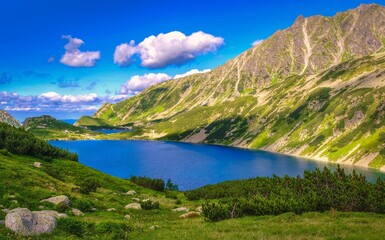 Naklejka na ściany i meble Beautiful blue lake in polish mountains. Picturesque view stretches over lakes in the Five Pond Valley and mountain ridge in Tatra mountains, Poland.