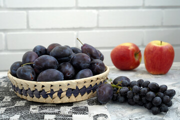 blue grapes and plums, red apples on the kitchen table. ripe vitamin gifts of autumn.