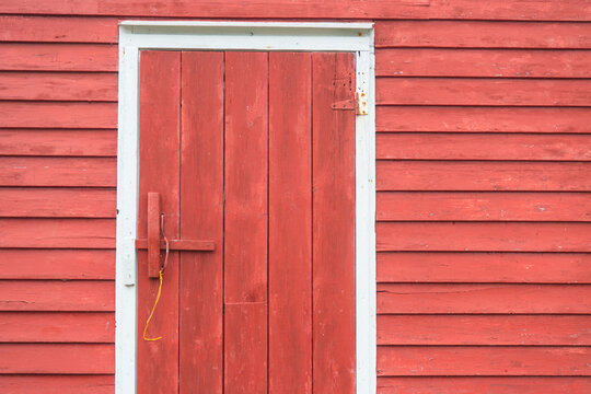Close-up of a wooden door in a red wooden-sided fish house; Battle Harbour, Newfoundland and Labrador, Canada