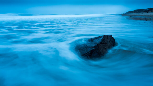 Surf swirling around a rock by the shore at dawn on Marconi Beach; Welfleet, Massachusetts, United States of America