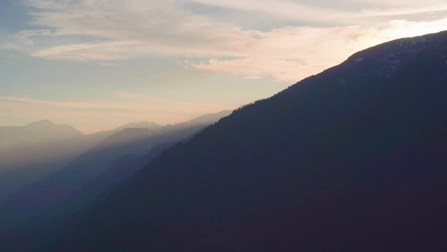 panning shot showing beautiful sunset colors in hampta village kullu manali with mighty himalaya mountains lost in fog