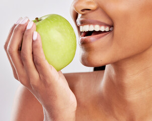 Woman, apple in hand and health with nutrition and fruit closeup, healthy food and diet on studio background. Weight loss, organic and fresh produce with happy female mouth, wellness and lifestyle