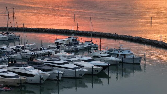 MONFALCONE, ITALY - APRIL, 2023: Sailing yacht moored off the coast Adriatic sea in Italy at sunset. Drone aerial view, cinematic frame. Romantic atmosphere. Calm and pacifying scene.