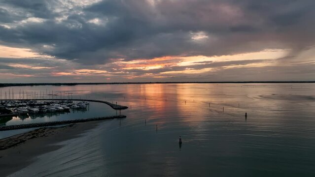 MONFALCONE, ITALY - APRIL, 2023: Sailing yacht moored off the coast Adriatic sea in Italy at sunset. Drone aerial view, cinematic frame. Romantic atmosphere. Calm and pacifying scene.