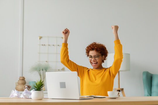 Excited happy african american woman euphoric winner. Girl student looking at laptop passed exam reading great news getting good result winning online bid feeling amazed at home. Winning gesture
